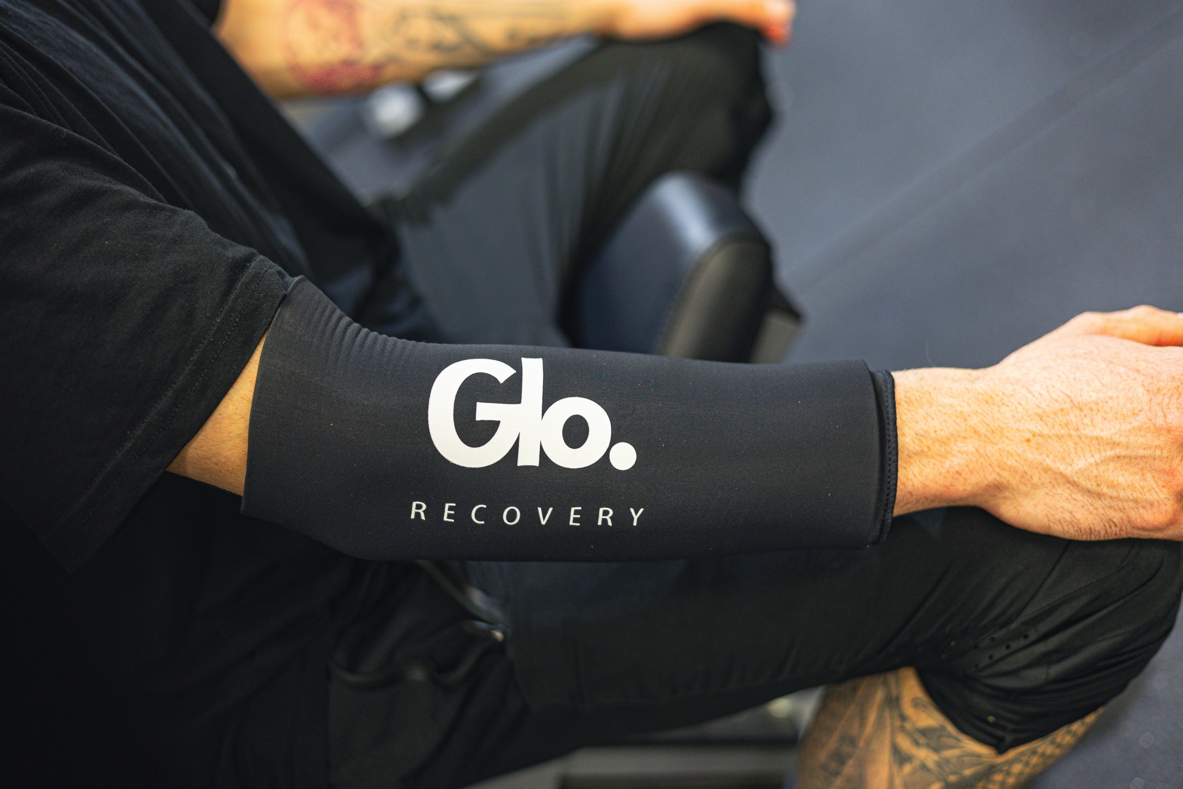 Person wearing a black sleeve with 'Glo. Recovery' branding, sitting in a vehicle.